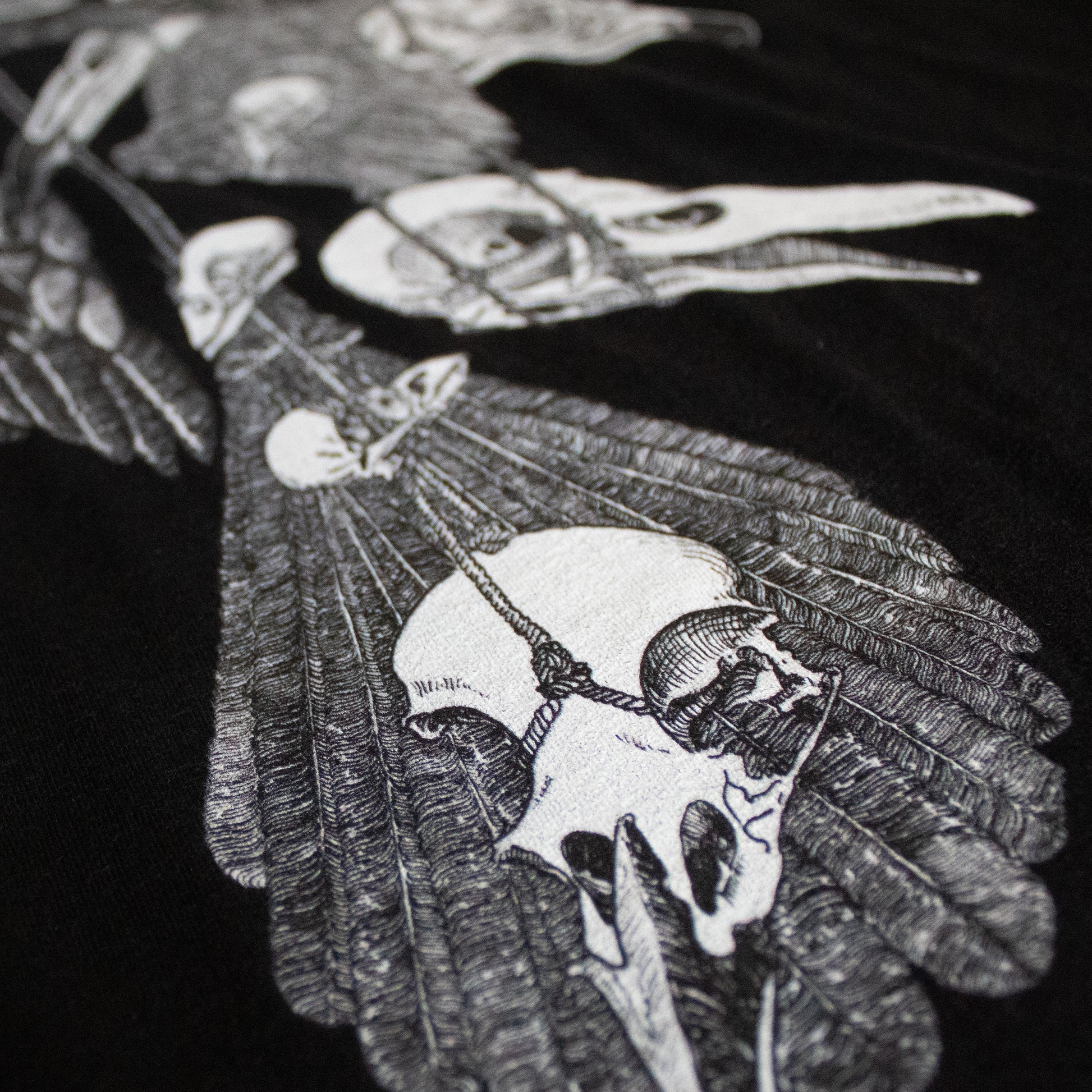 Close-up on black and white, tattoo inspired, gothic, witchy, pagan art on clothing piece. Birds & Bones collection features nature and death inspired artwork on t-shirts and sweathirts.