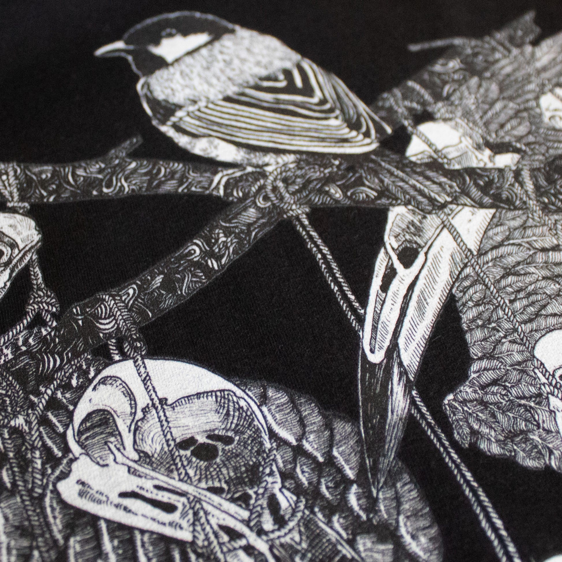 Close-up on black and white, tattoo inspired, gothic, witchy, pagan art on clothing piece. Birds & Bones collection features nature and death inspired artwork on t-shirts and sweathirts.