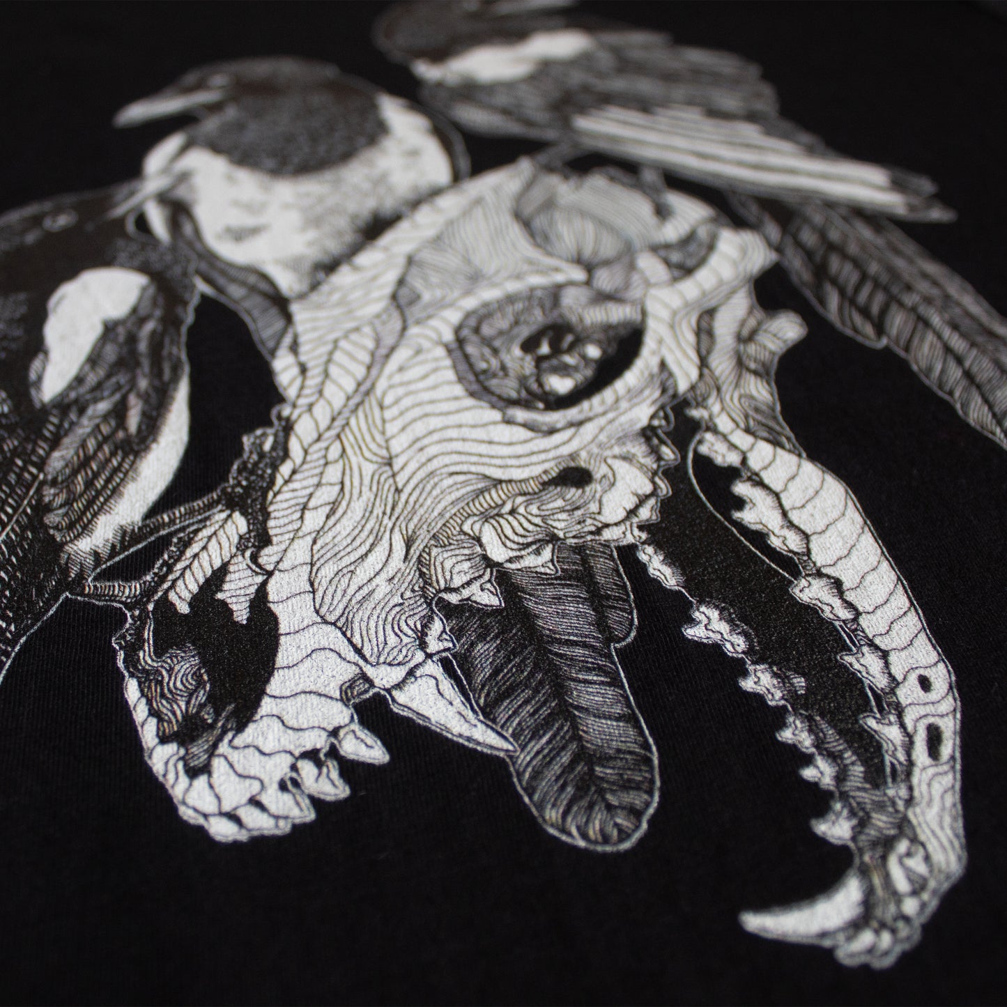 Close-up on black and white, tattoo inspired, gothic, witchy, pagan art on clothing piece. Birds & Bones collection features nature and death inspired artwork on t-shirts and sweathirts.