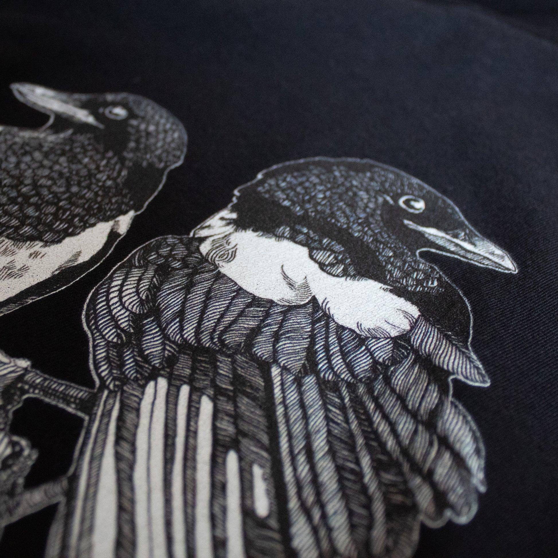 Close-up on black and white, tattoo inspired, gothic, witchy, pagan art on clothing piece. Birds & Bones collection features nature and death inspired artwork on t-shirts and sweathirts.