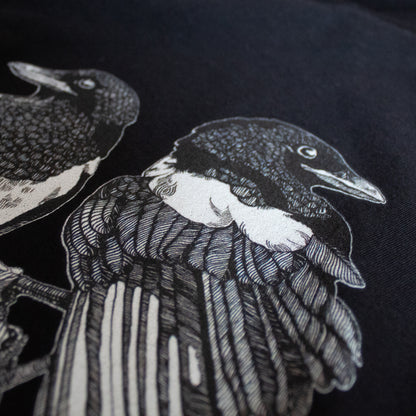 Close-up on black and white, tattoo inspired, gothic, witchy, pagan art on clothing piece. Birds & Bones collection features nature and death inspired artwork on t-shirts and sweathirts.